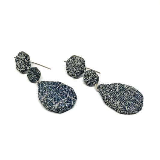 Two "Patched Coronation (Street)" earrings by Louise Perrone. Each earring features three textured, fabric-patched geometric shapes on a thin post.