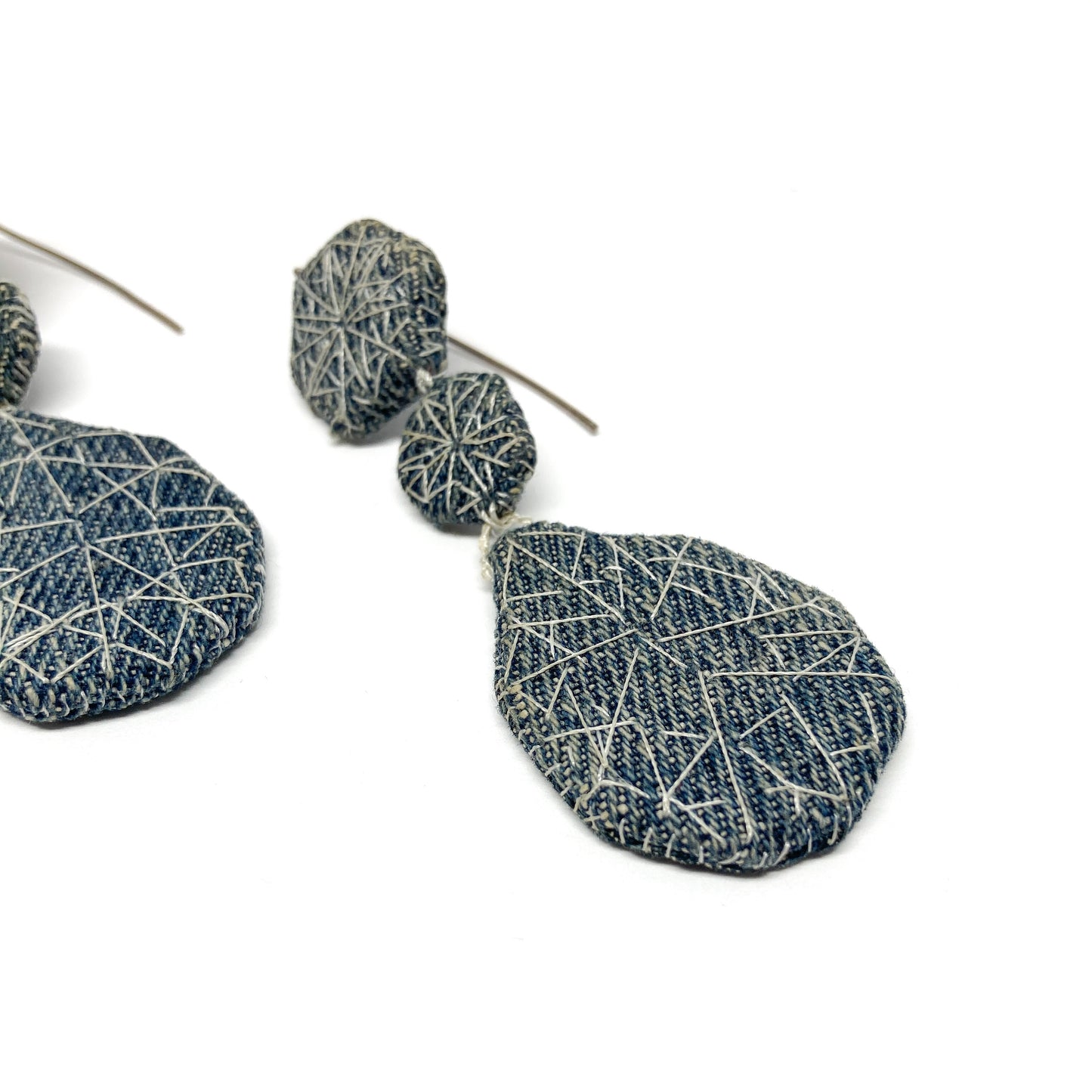 Close-up of one "Patched Coronation (Street)" earring by Louise Perrone. Features three textured, fabric-patched geometric shapes on a thin post.