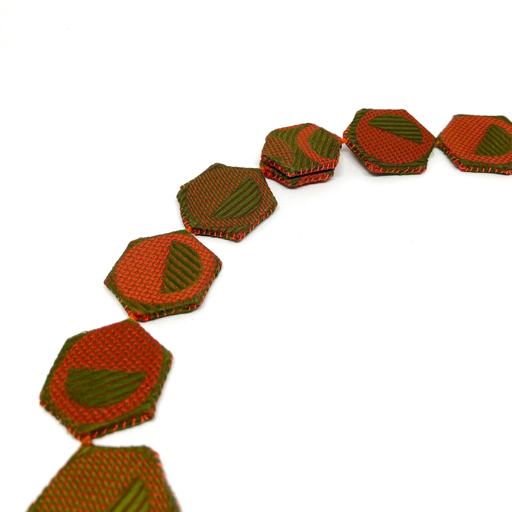 Detailed view of the ReAuthorized Border Necklace, highlighting the stitching and geometric design of the connected hexagons.