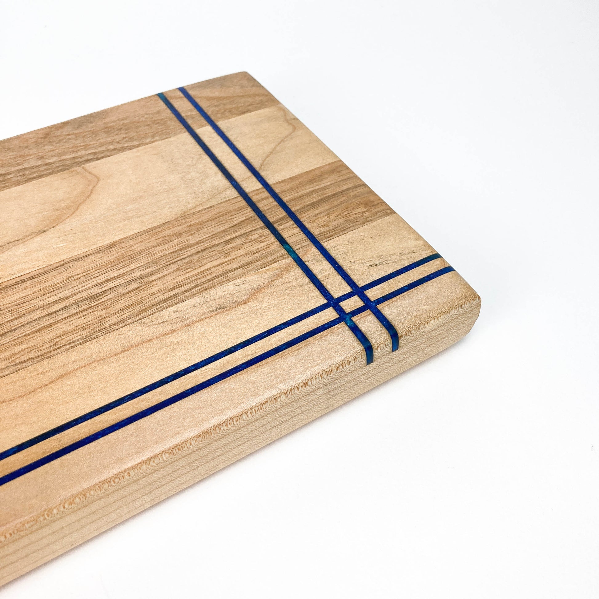 Detailed view of the Butternut Railroad Charcuterie Board showing intersecting blue resin inlays at the corner.