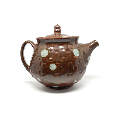 A brown ceramic teapot with a lid, handle, and spout, decorated with scattered light-colored circular dots.