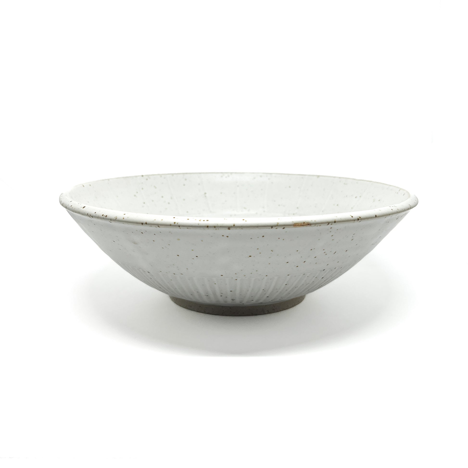 A speckled light-toned ceramic bowl with subtle vertical ridges and a visible unglazed base.