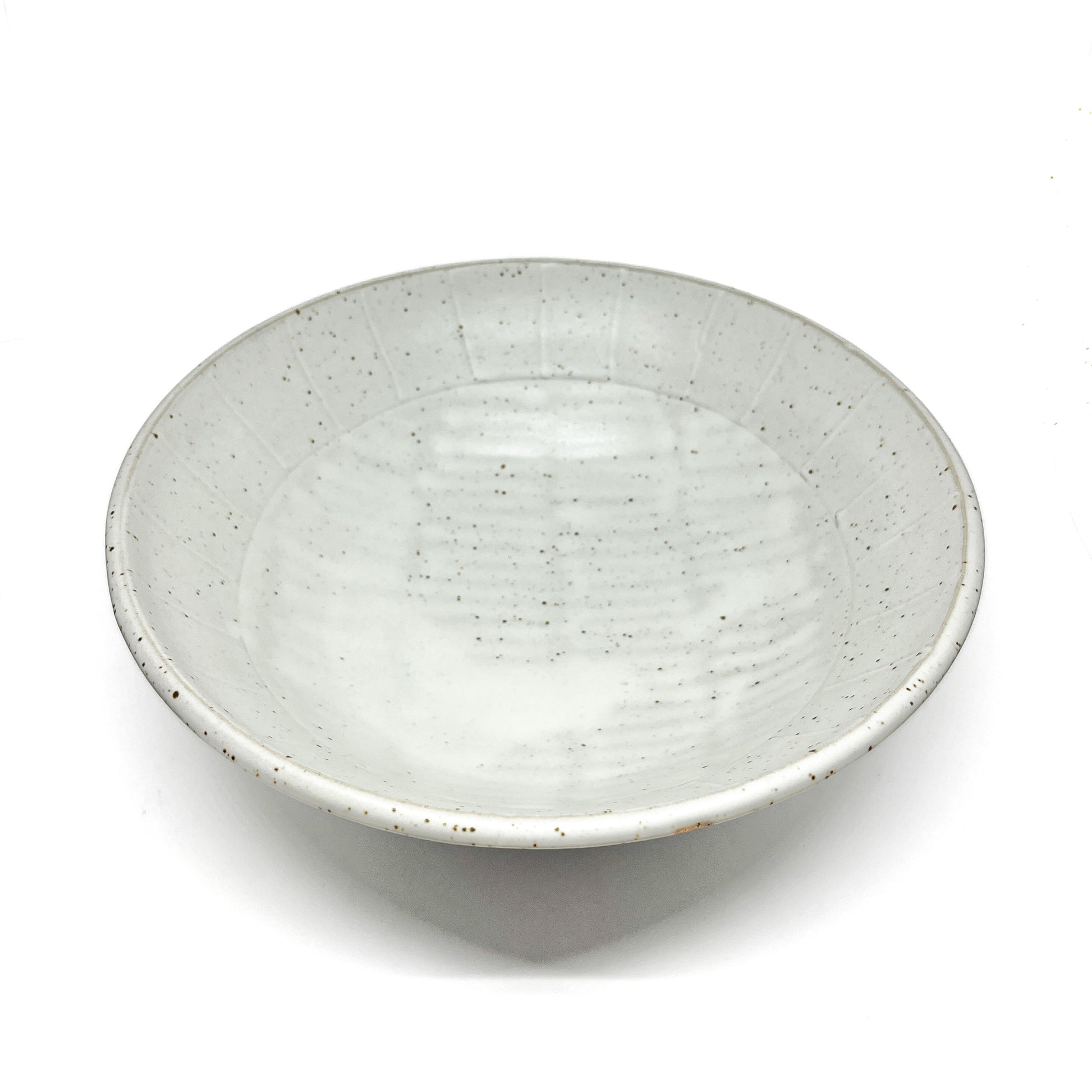 Top-down view of a shallow, speckled light ceramic bowl with subtle concentric rings on the interior.