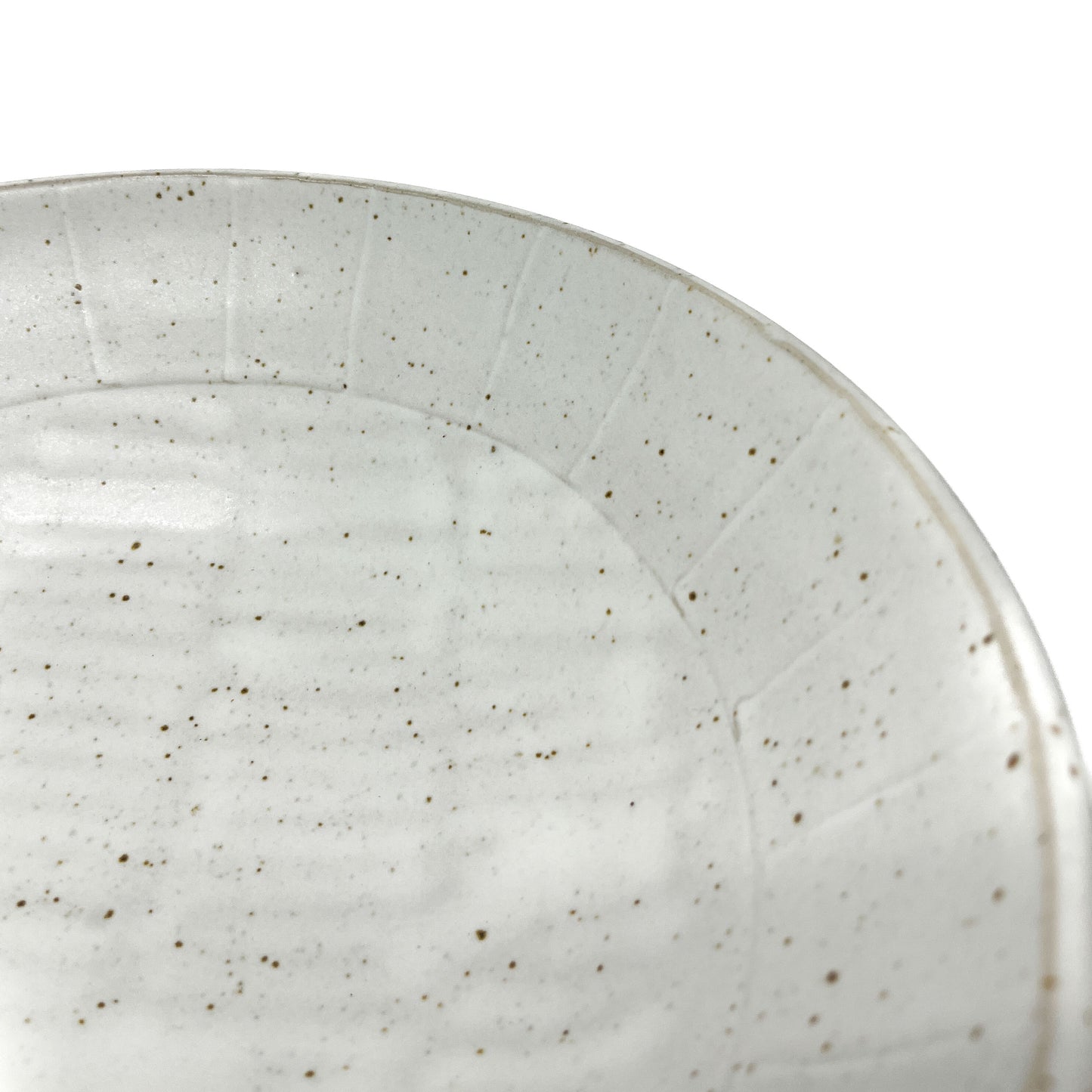 Close-up of a speckled light ceramic bowl's interior showing subtle concentric rings and texture.