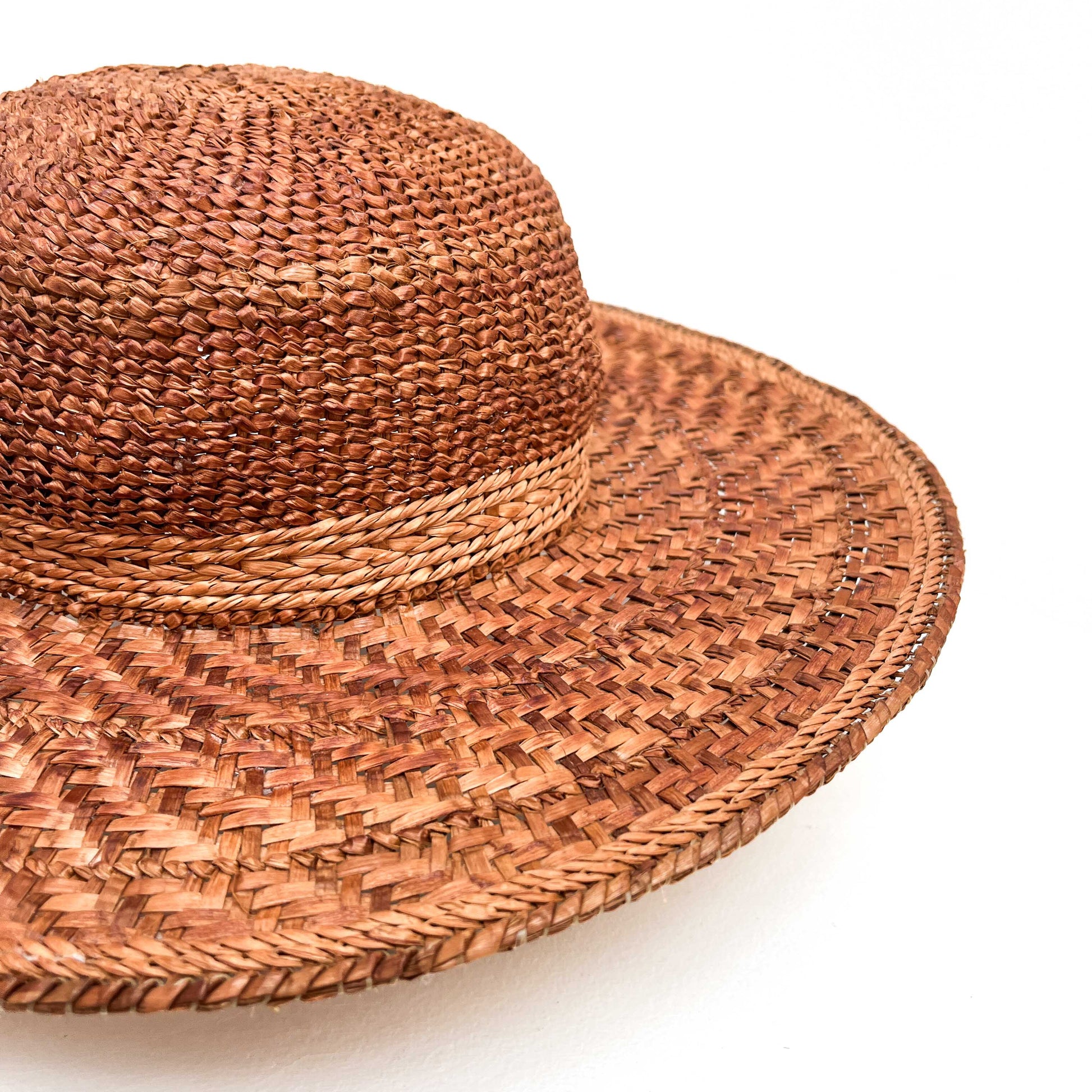 A close-up of a wide-brimmed woven hat with a rounded crown, showing the texture of the weave.