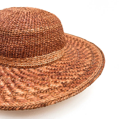A close-up of a wide-brimmed woven hat with a rounded crown, showing the texture of the weave.