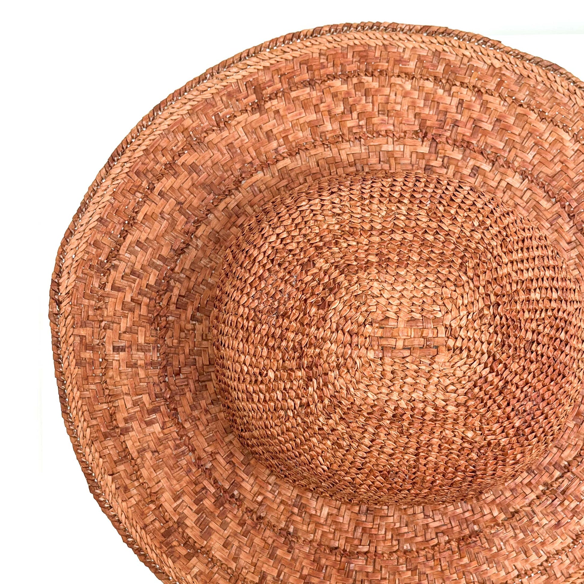 A top-down view of a woven hat, showing the crown and wide brim's intricate weave.