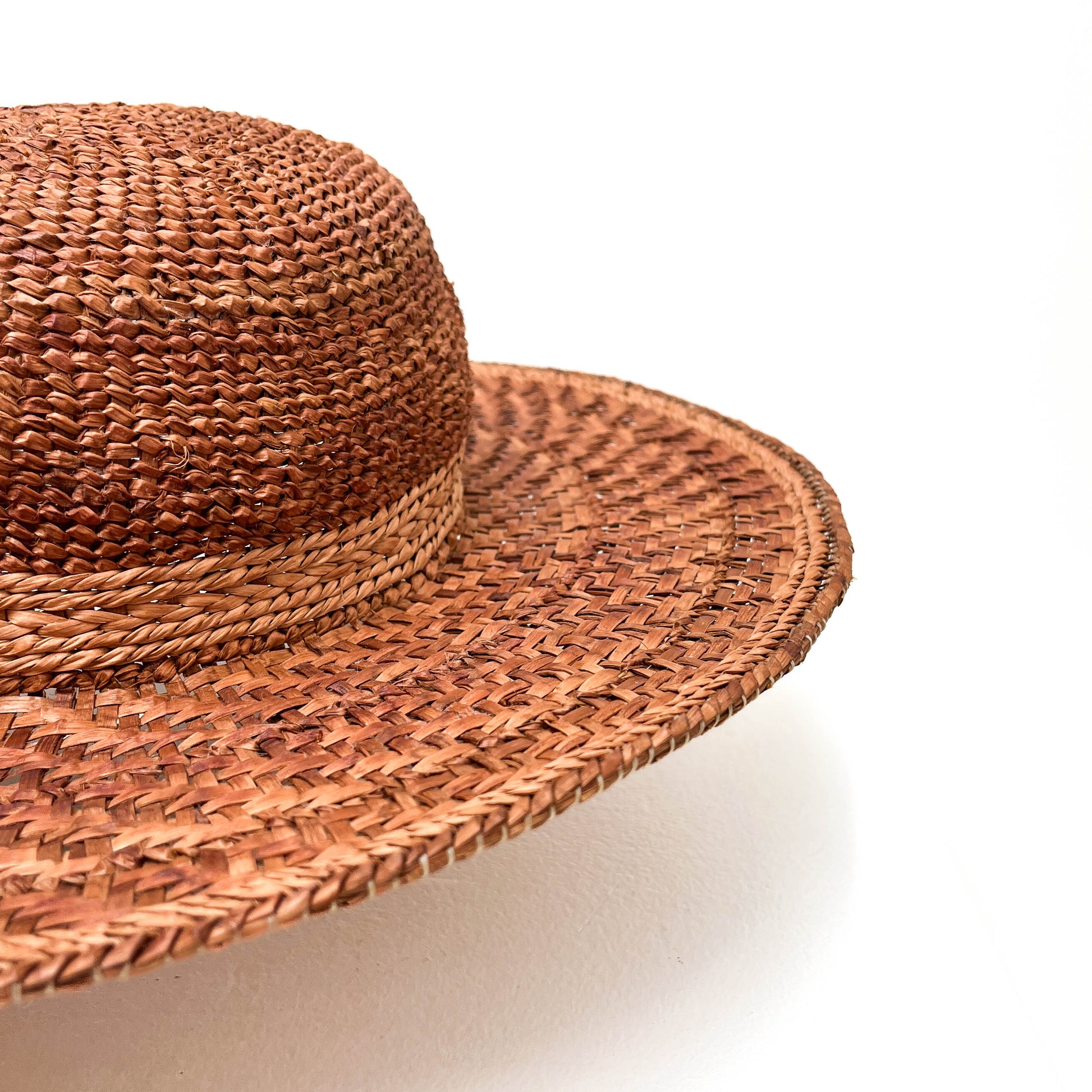 A close-up of a woven hat's crown and brim, highlighting the intricate weave and band detail.