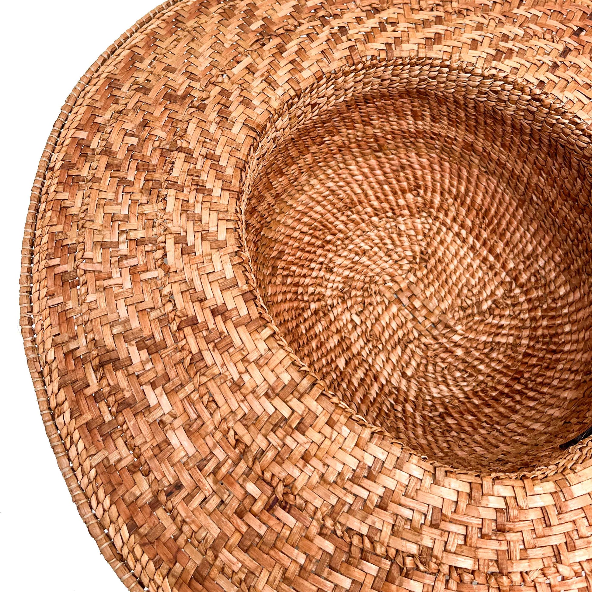 A close-up, angled view of the inside of a woven hat, showing the texture of the weave.