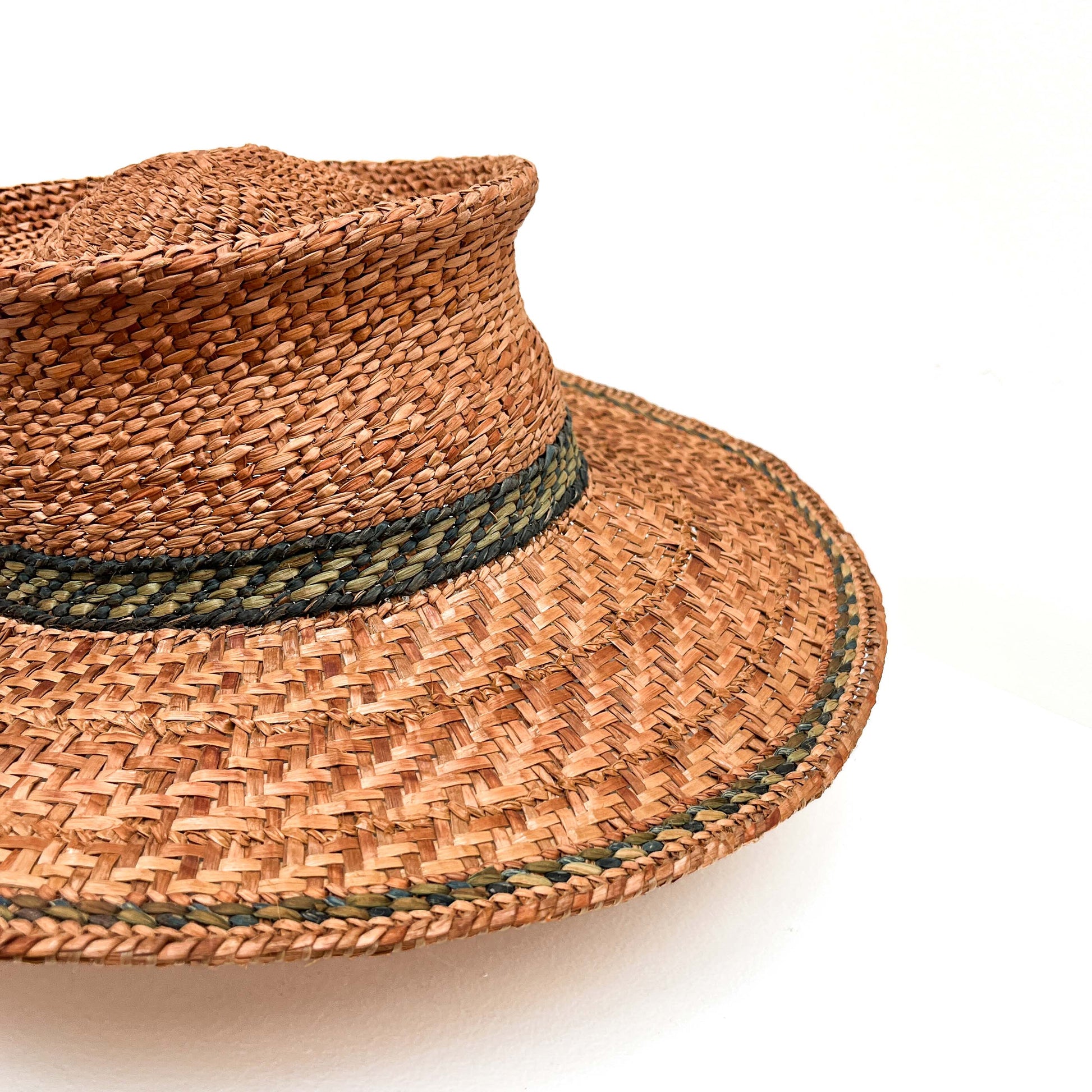 A close-up of a woven hat with a green band, highlighting the texture and detail.