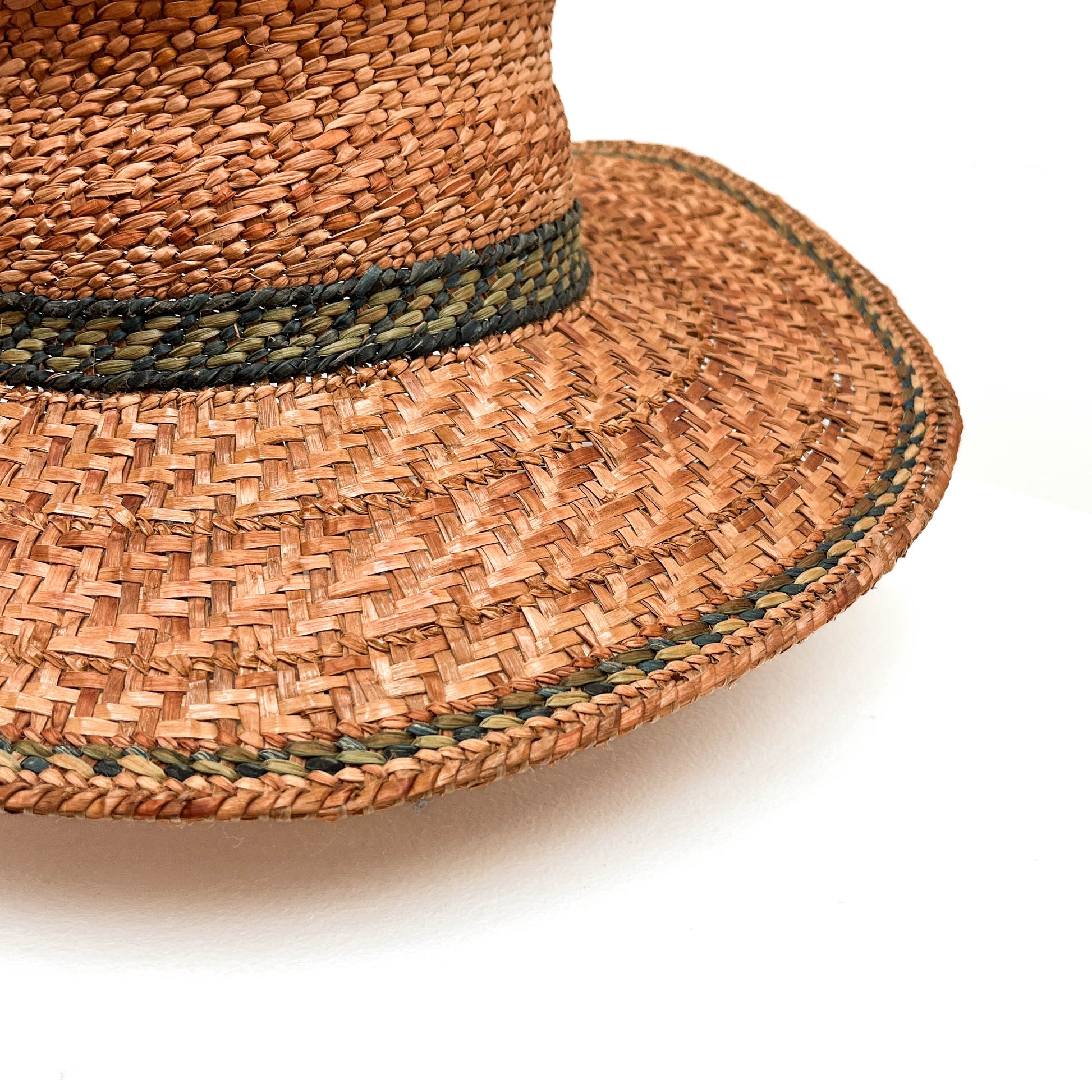 A close-up of a woven hat with a green band, highlighting the texture and detail.