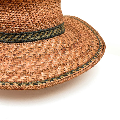 A close-up of a woven hat with a green band, highlighting the texture and detail.
