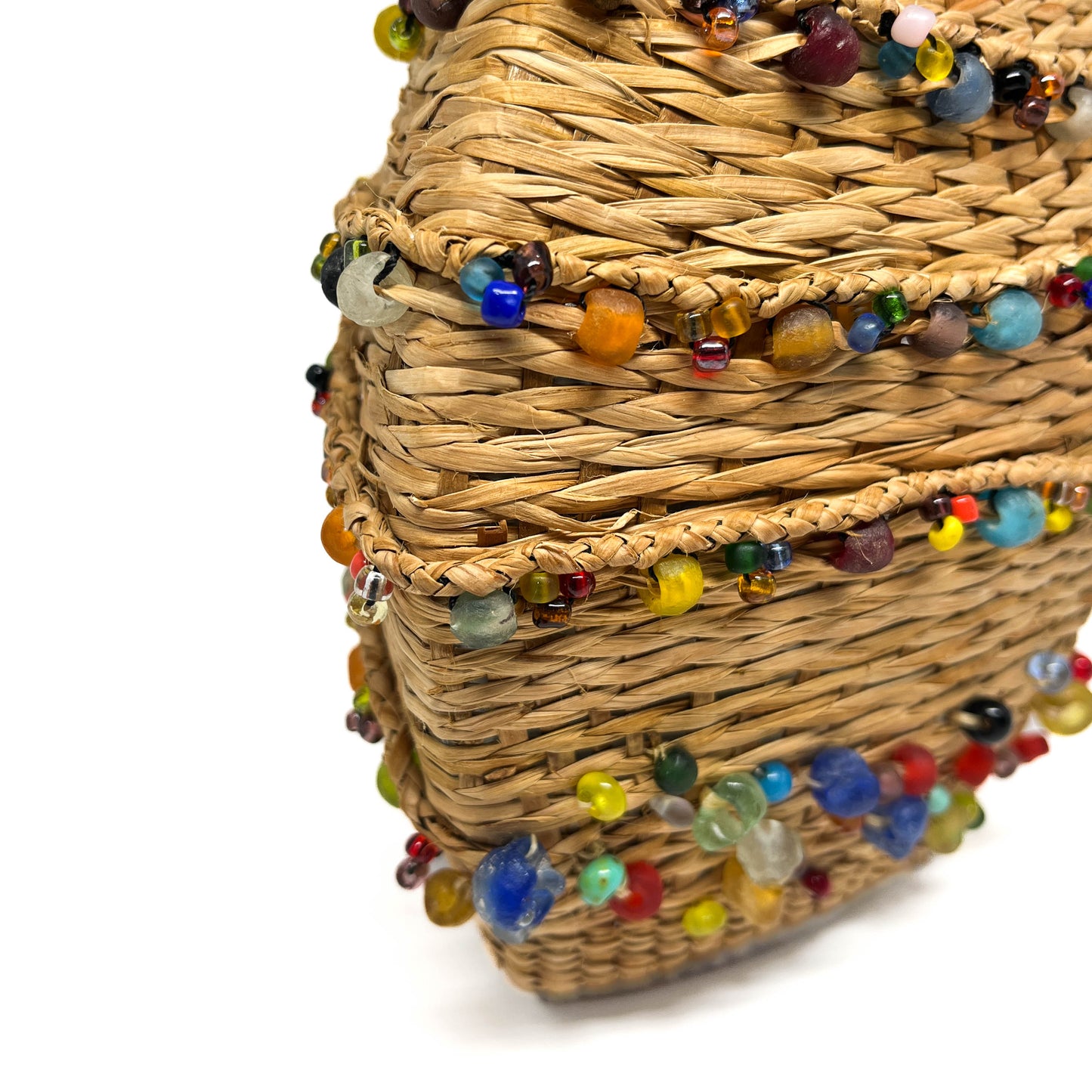 A close-up of a woven decanter base, showing texture and colorful beads.
