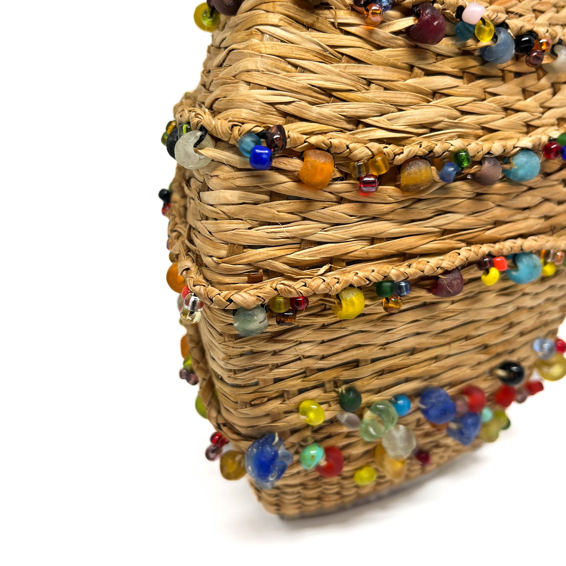 A close-up of a woven decanter base, showing texture and colorful beads.