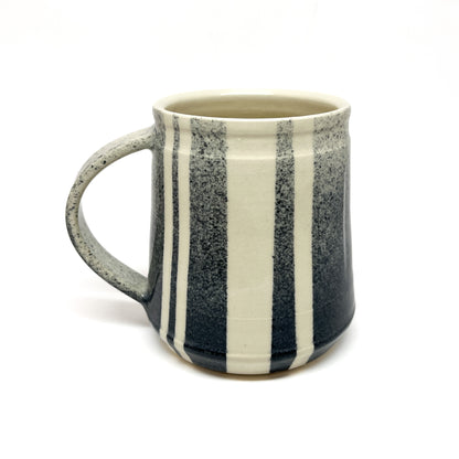 Upright ceramic mug with vertical stripes and a handle.