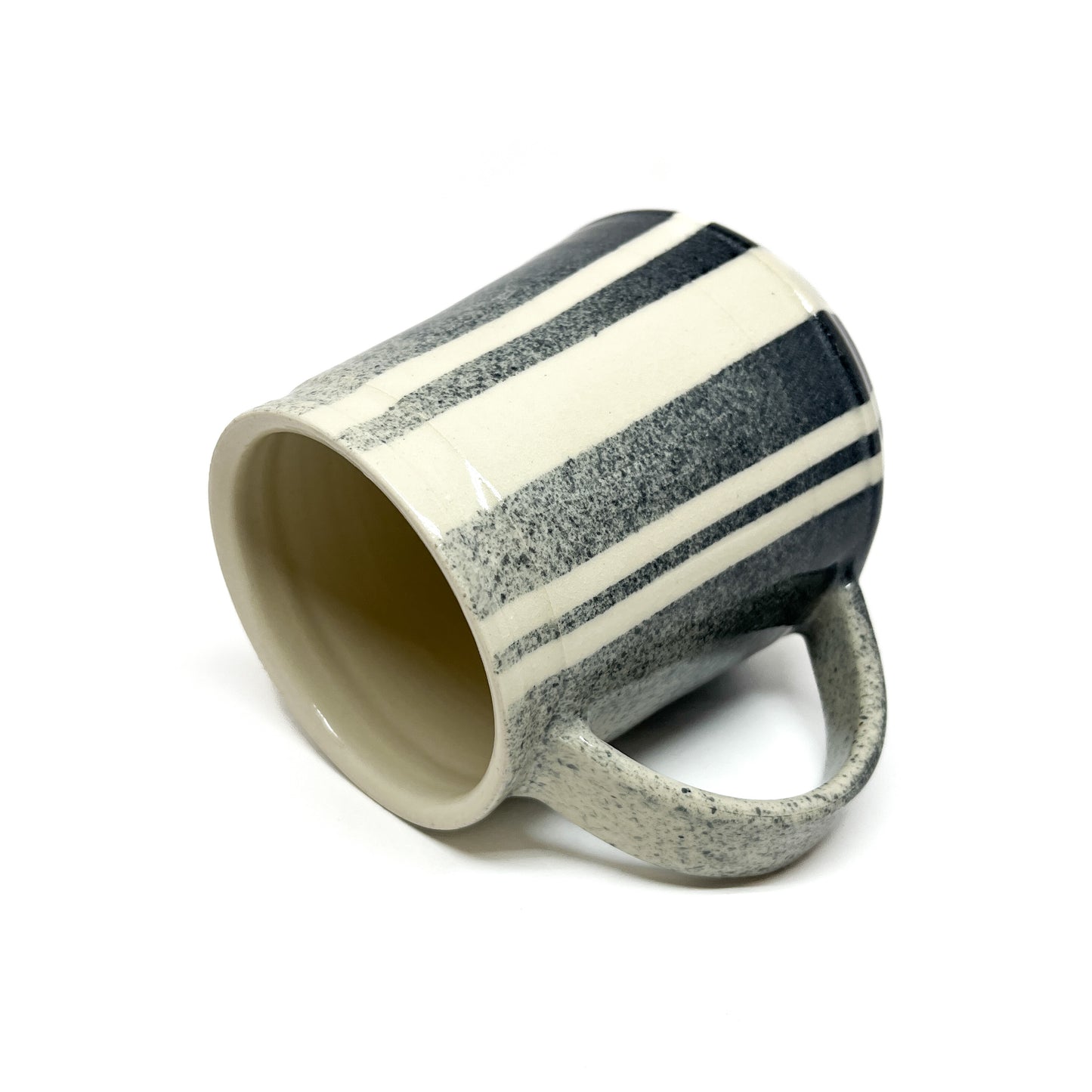 Tilted ceramic mug with diagonal stripes and a handle, showcasing its inner surface.