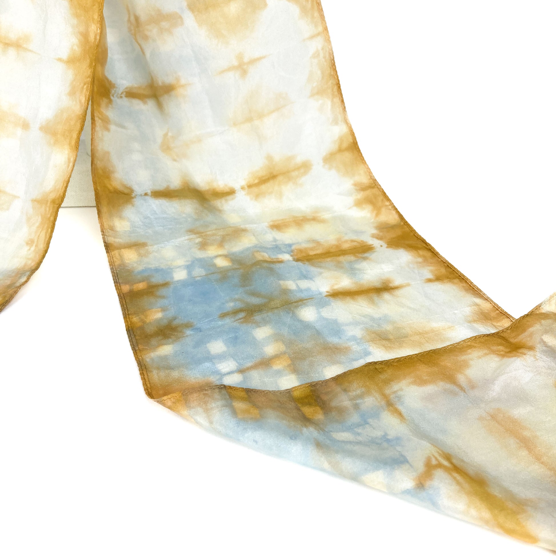 A section of a cutch tree bark silk scarf reveals its delicate, horizontally patterned shibori tie-dye.
