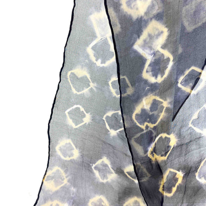 A close-up shows the delicate fabric and resist shibori pattern of a Black Bean Hull silk scarf with outlined squares.