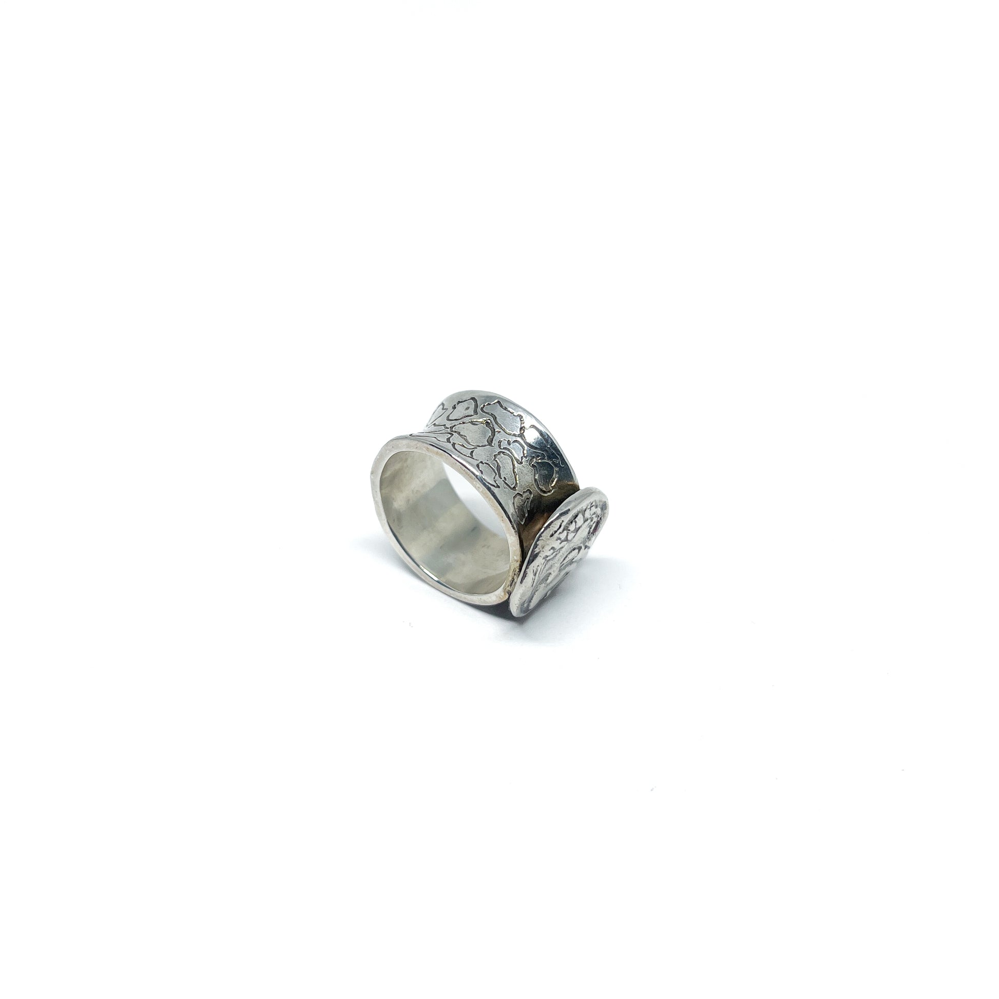 A silver ring with a wide, textured band and an attached antique coin featuring a detailed profile.