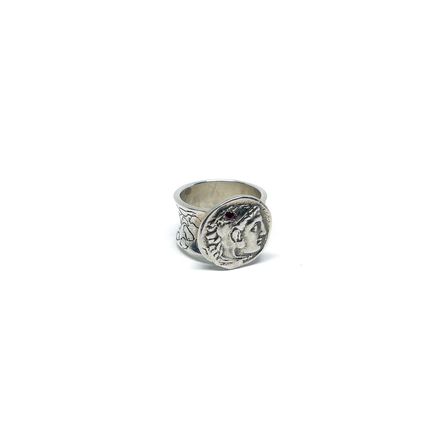A silver ring featuring an antique coin with a profile of a person and a decorative band.