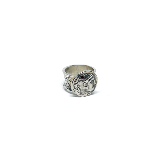 A silver ring featuring an antique coin with a profile of a person and a decorative band.
