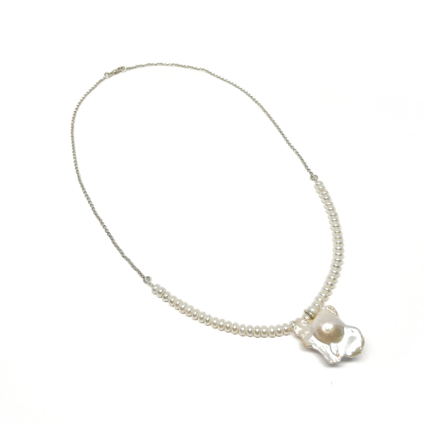 A pearl necklace with a chain on one side transitioning to small pearls, featuring a large, luminous baroque pearl pendant.