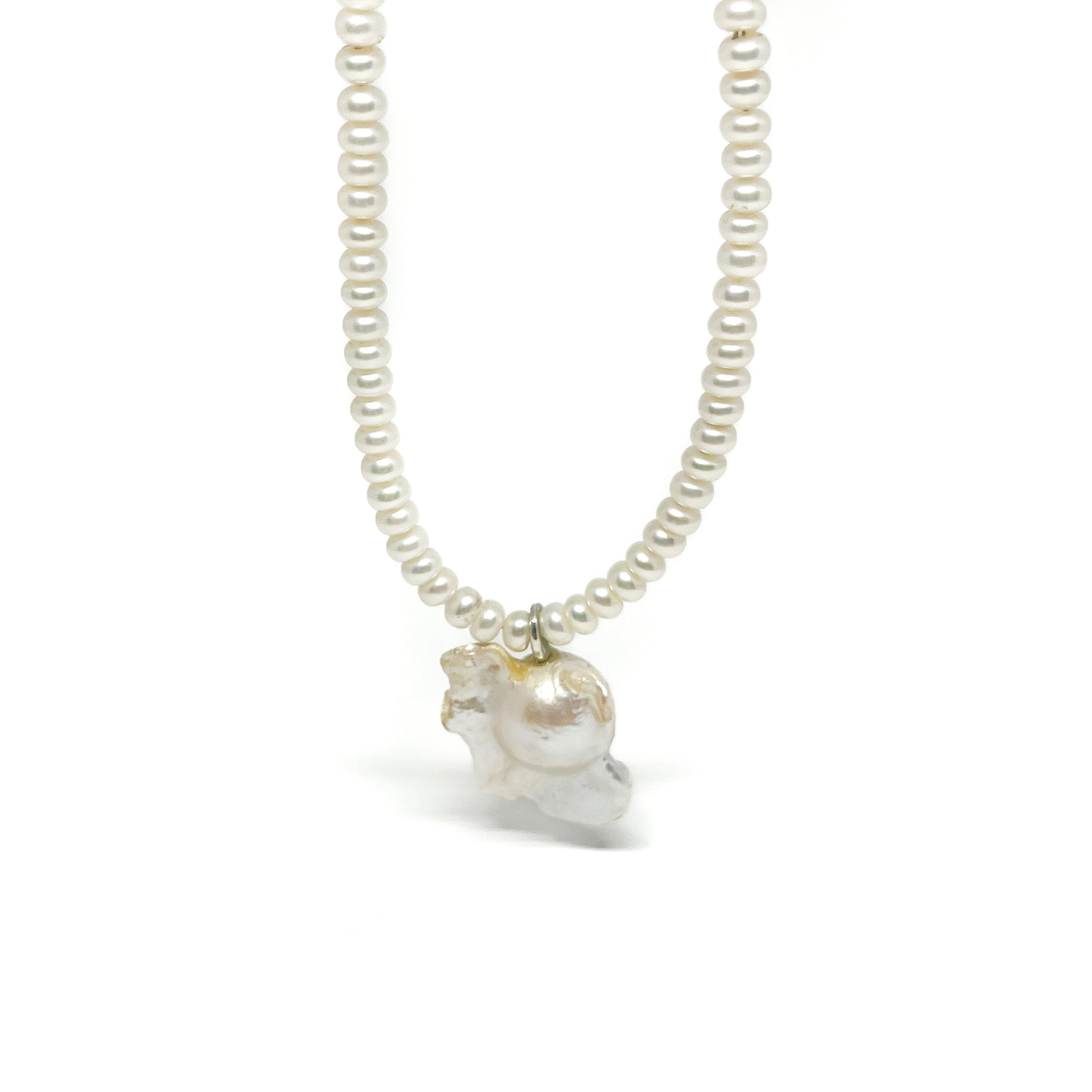 A pearl necklace featuring small, round pearls and a larger, organically shaped baroque pearl charm.