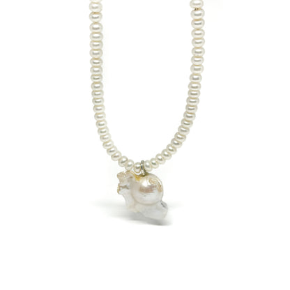 A pearl necklace featuring small, round pearls and a larger, organically shaped baroque pearl charm.