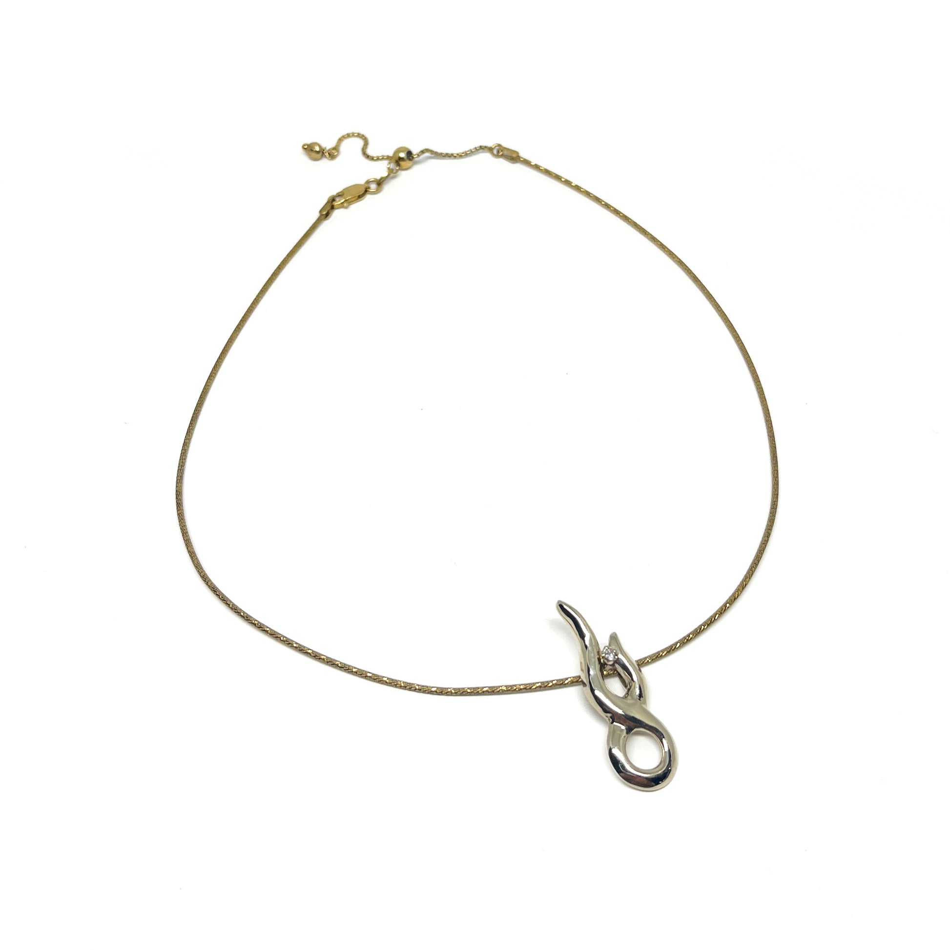 A gold-toned necklace with an adjustable chain and a modern, polished silver pendant featuring a small clear gem.