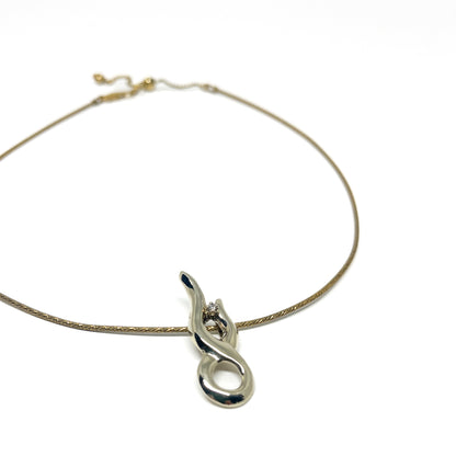 A delicate gold necklace featuring a polished silver abstract pendant with a small, sparkling stone.