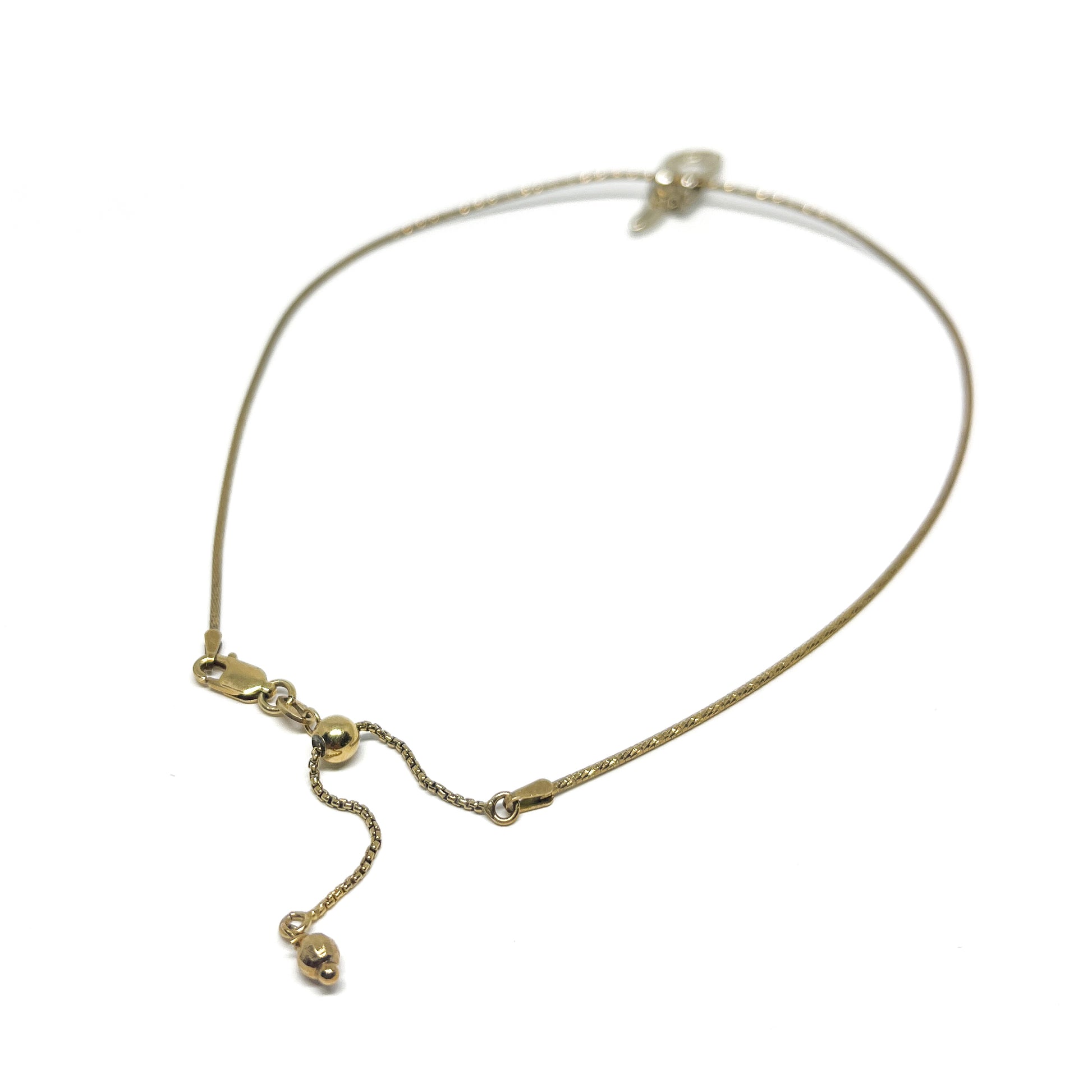 Close-up of a delicate gold necklace with an adjustable chain, clasp, and small dangling embellishments.