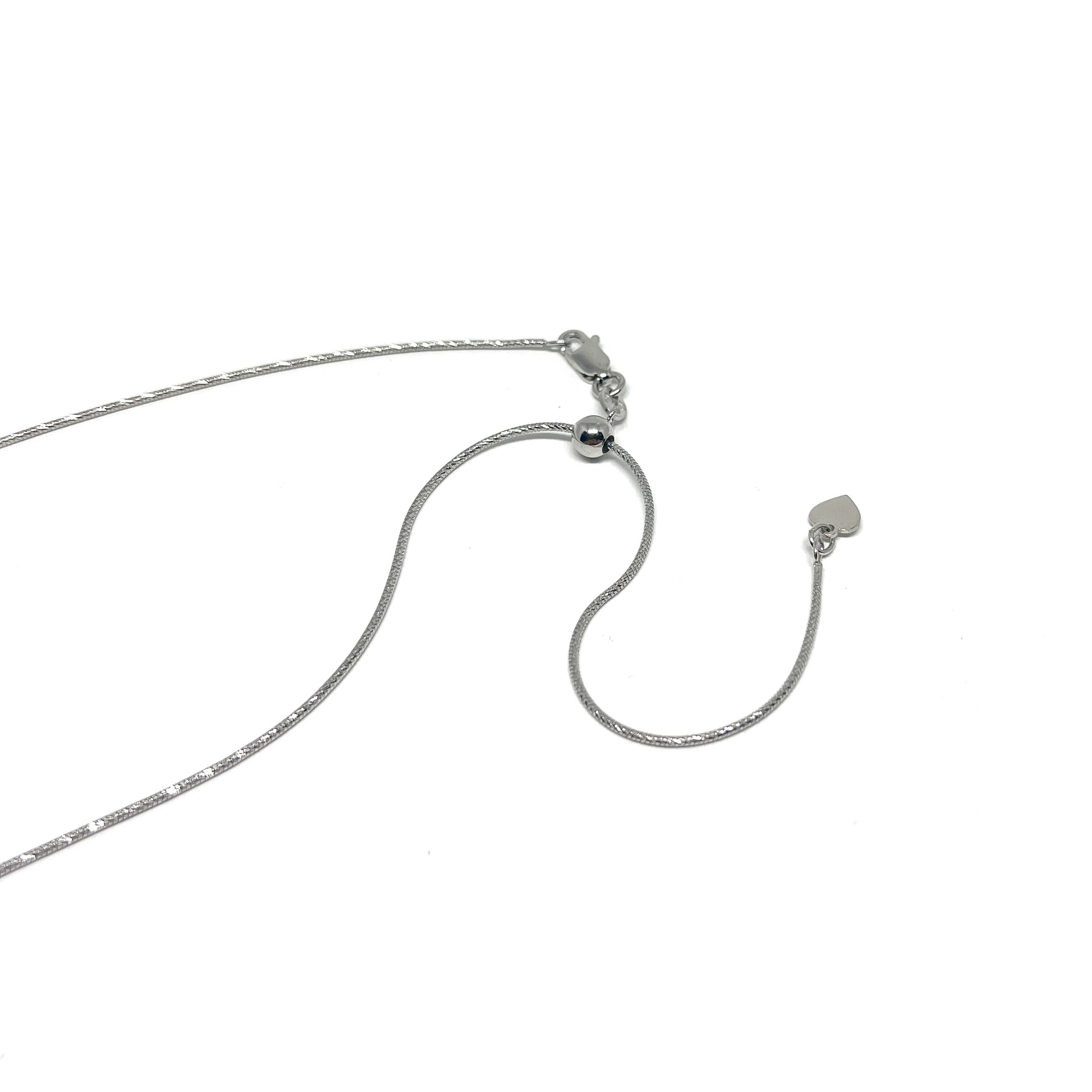 Close-up of a delicate silver necklace with an adjustable diamond-cut snake chain and a small heart charm at the end.