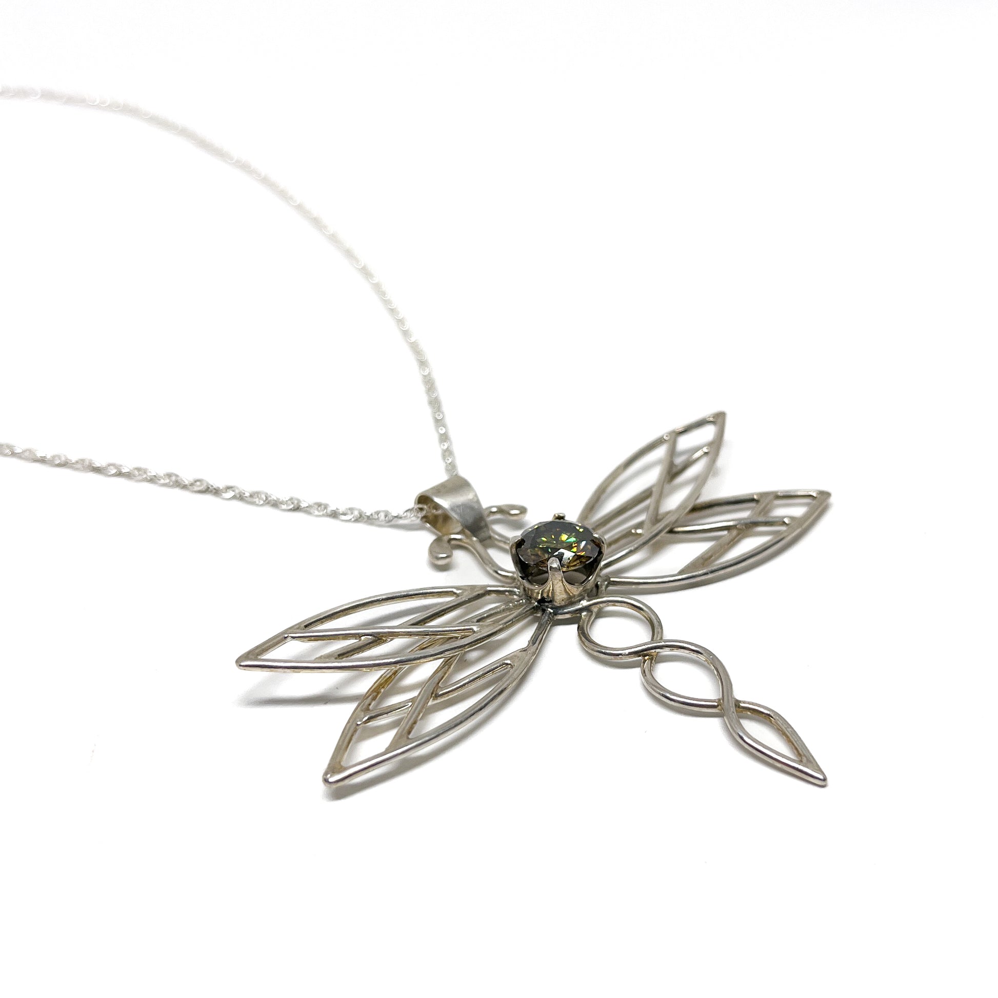 Silver dragonfly pendant necklace with a dark, multifaceted gemstone at its center.