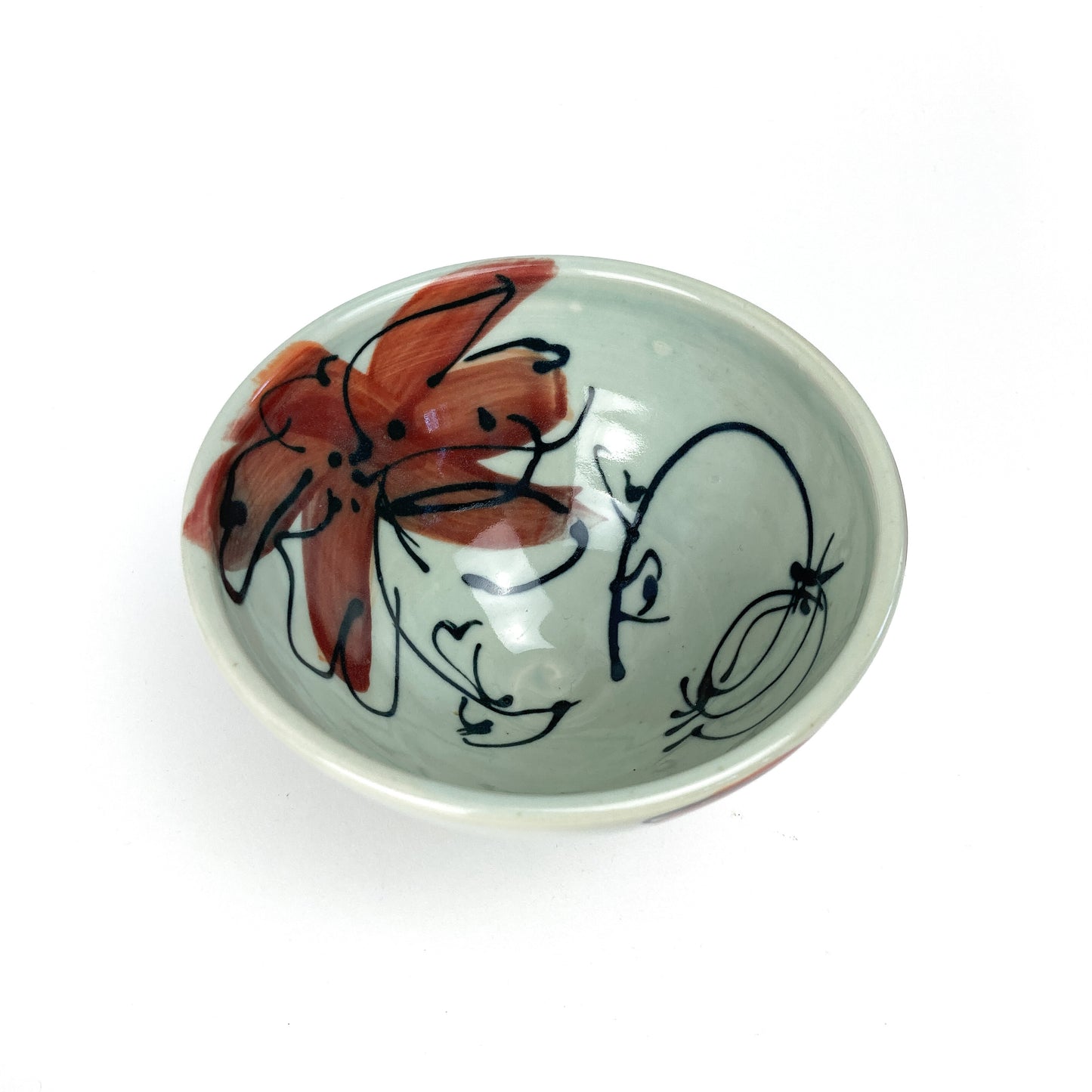 A small, round ceramic bowl with a hand-painted floral design on its interior. The bowl has a smooth, glazed finish.