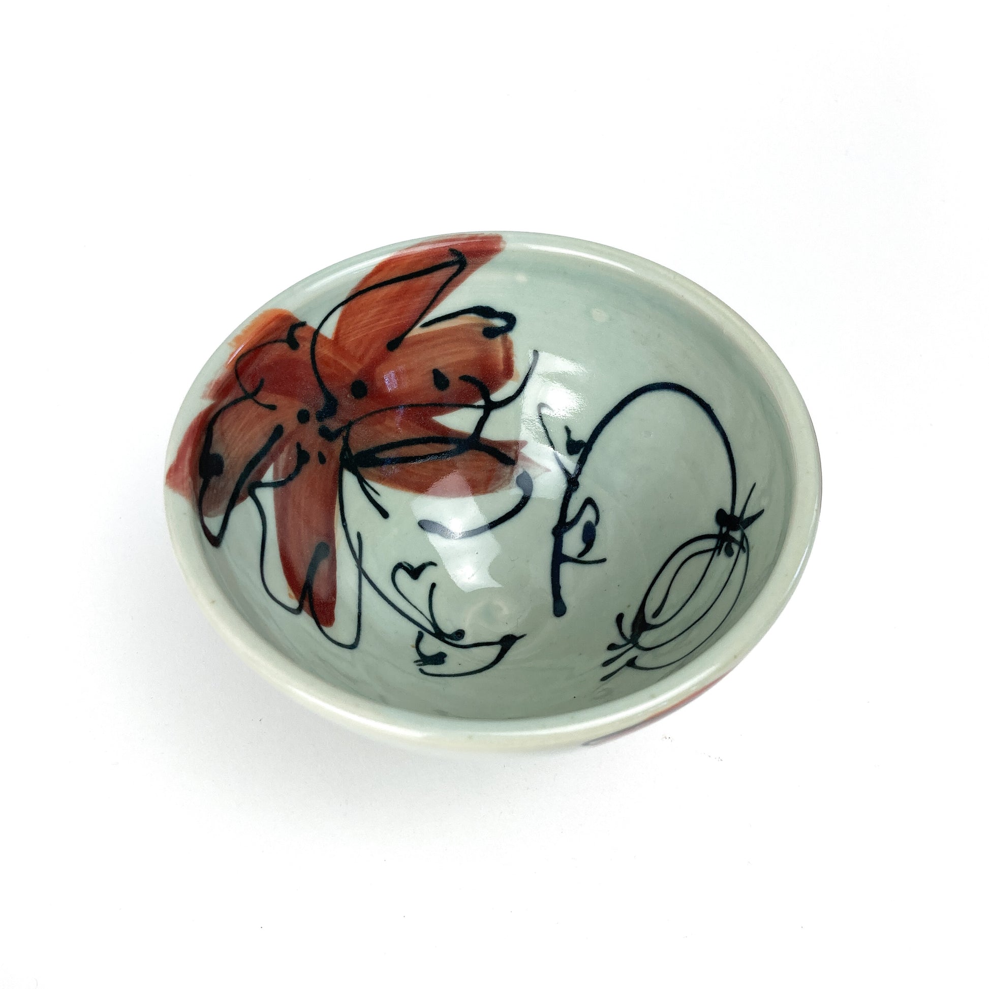 A small, round ceramic bowl with a hand-painted floral design on its interior. The bowl has a smooth, glazed finish.