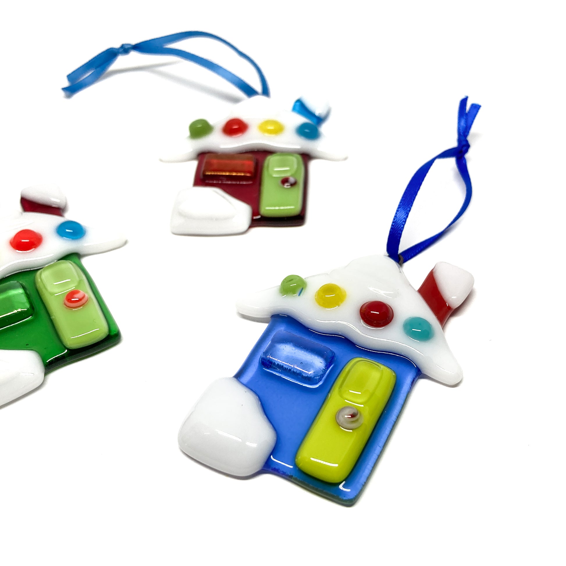 Three glass house ornaments with colorful details and blue ribbons, arranged diagonally.