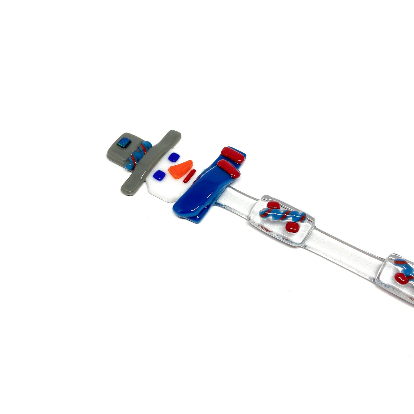 A glass stir stick shaped like a snowman, decorated with colorful glass pieces.