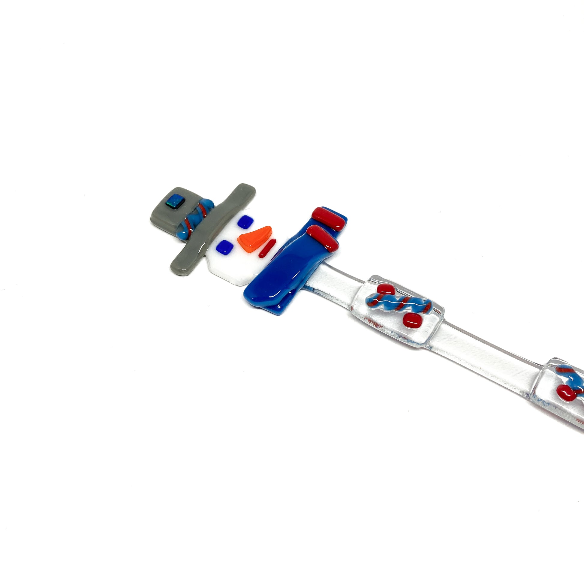 A glass stir stick shaped like a snowman, decorated with colorful glass pieces.
