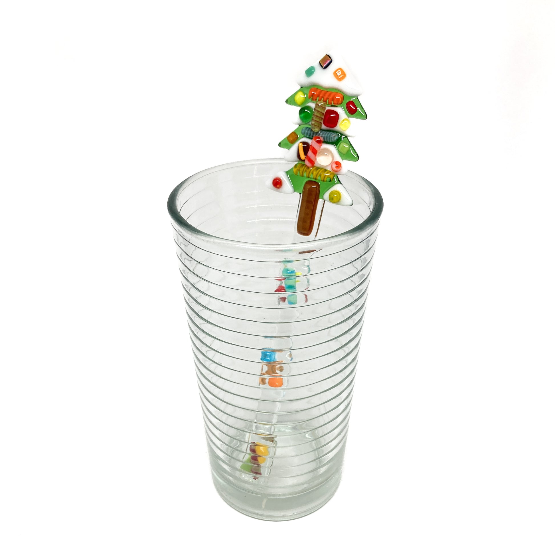 A glass stir stick shaped like a Christmas tree inside a clear glass.