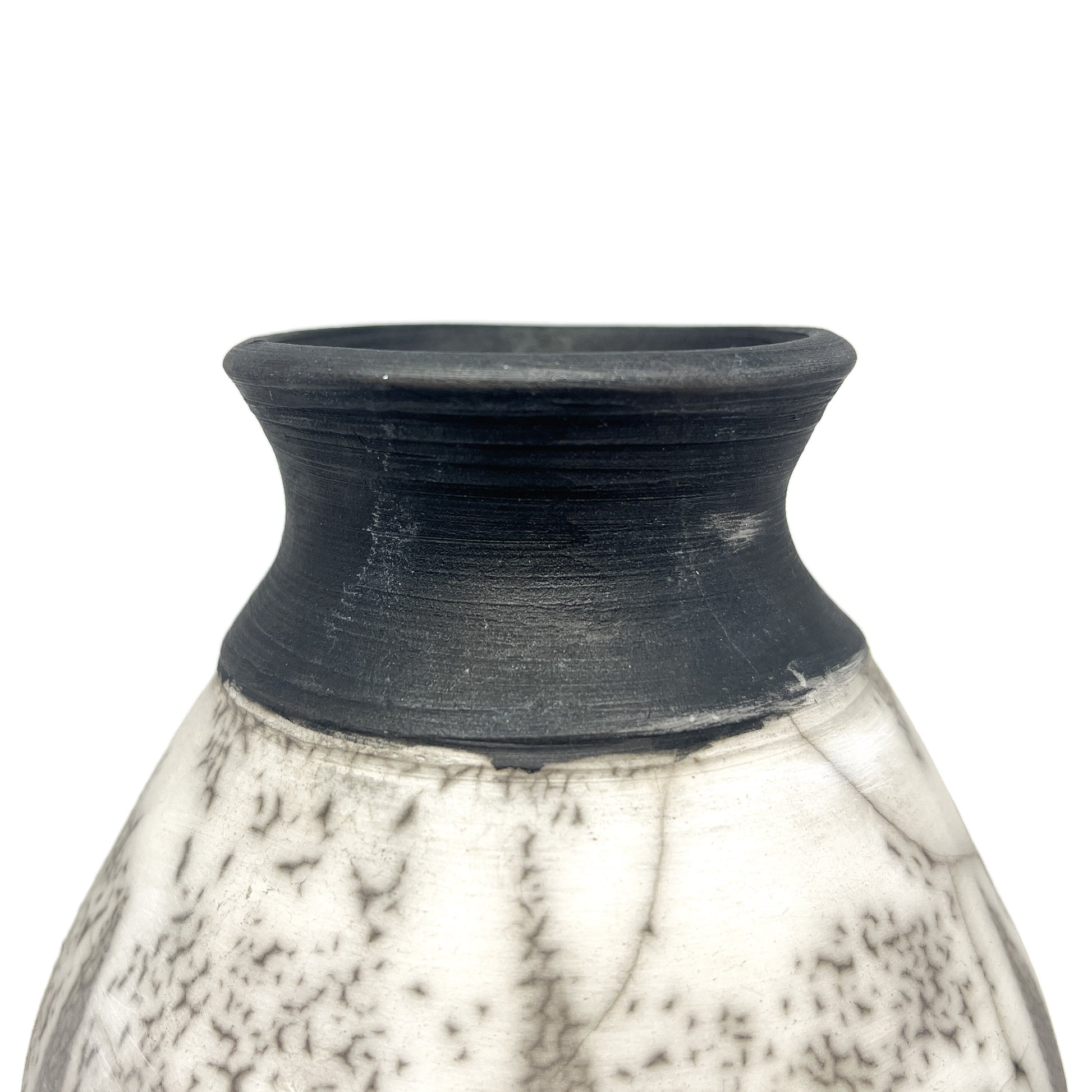 Close-up of the textured black neck and rim of a ceramic vase with a crackled white and black body.