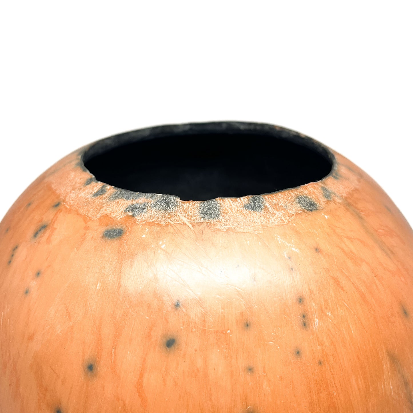 Close-up of a round ceramic vase showing the mottled glaze and dark interior opening.