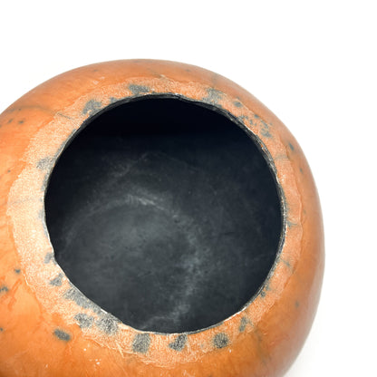 Top-down close-up of a round ceramic vase showing the mottled glaze and dark, textured interior.