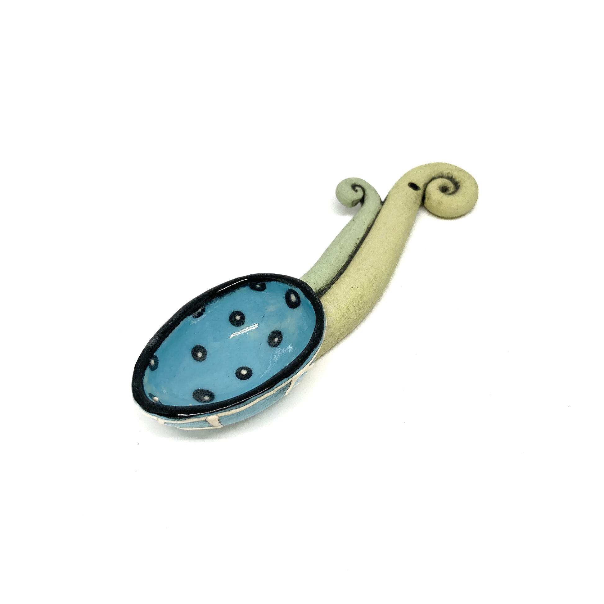Funky spoon with a polka-dot bowl and a curled sculptural handle in a whimsical, handcrafted style.