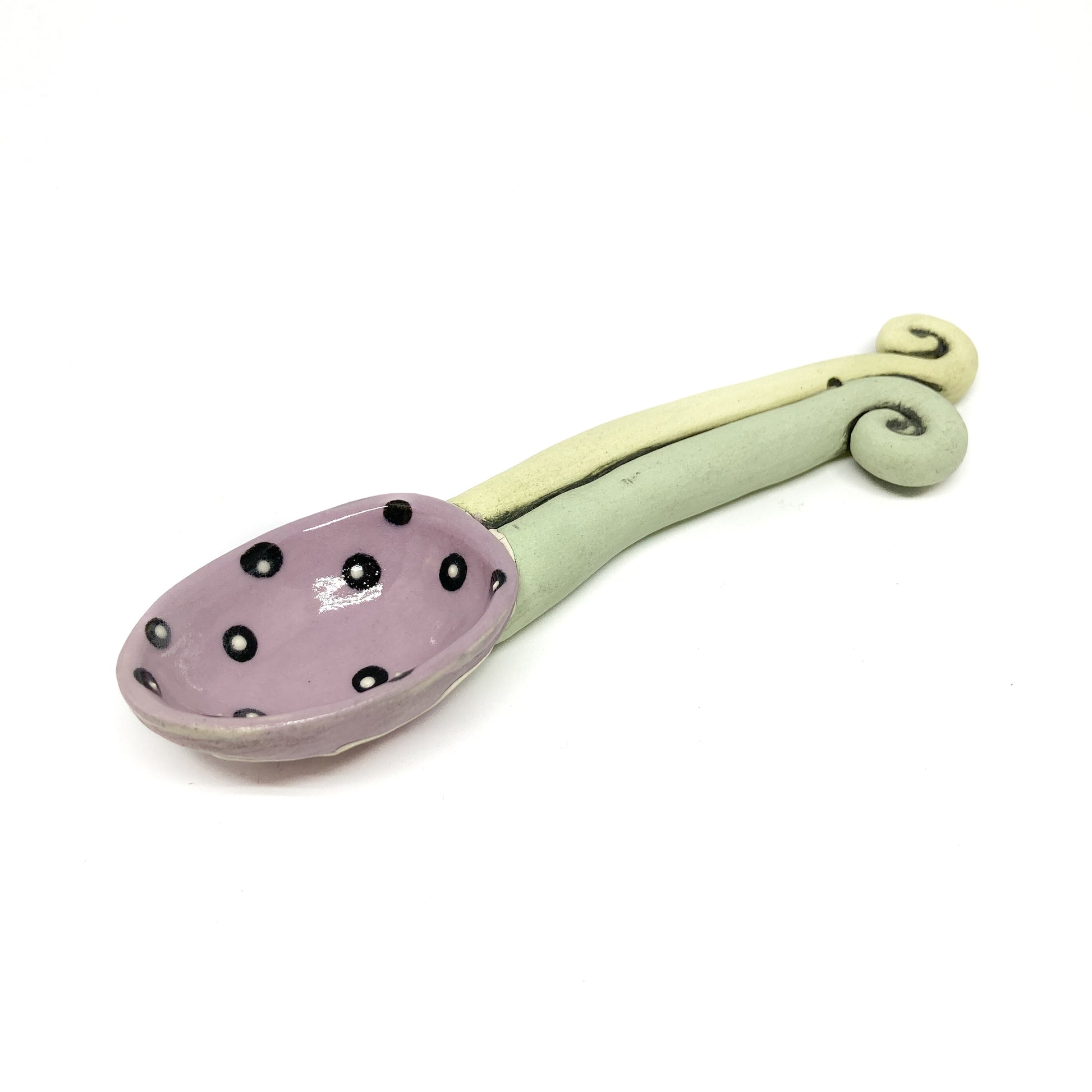 Funky spoon with a glossy polka-dot bowl and a curving, sculptural handle in a playful design.