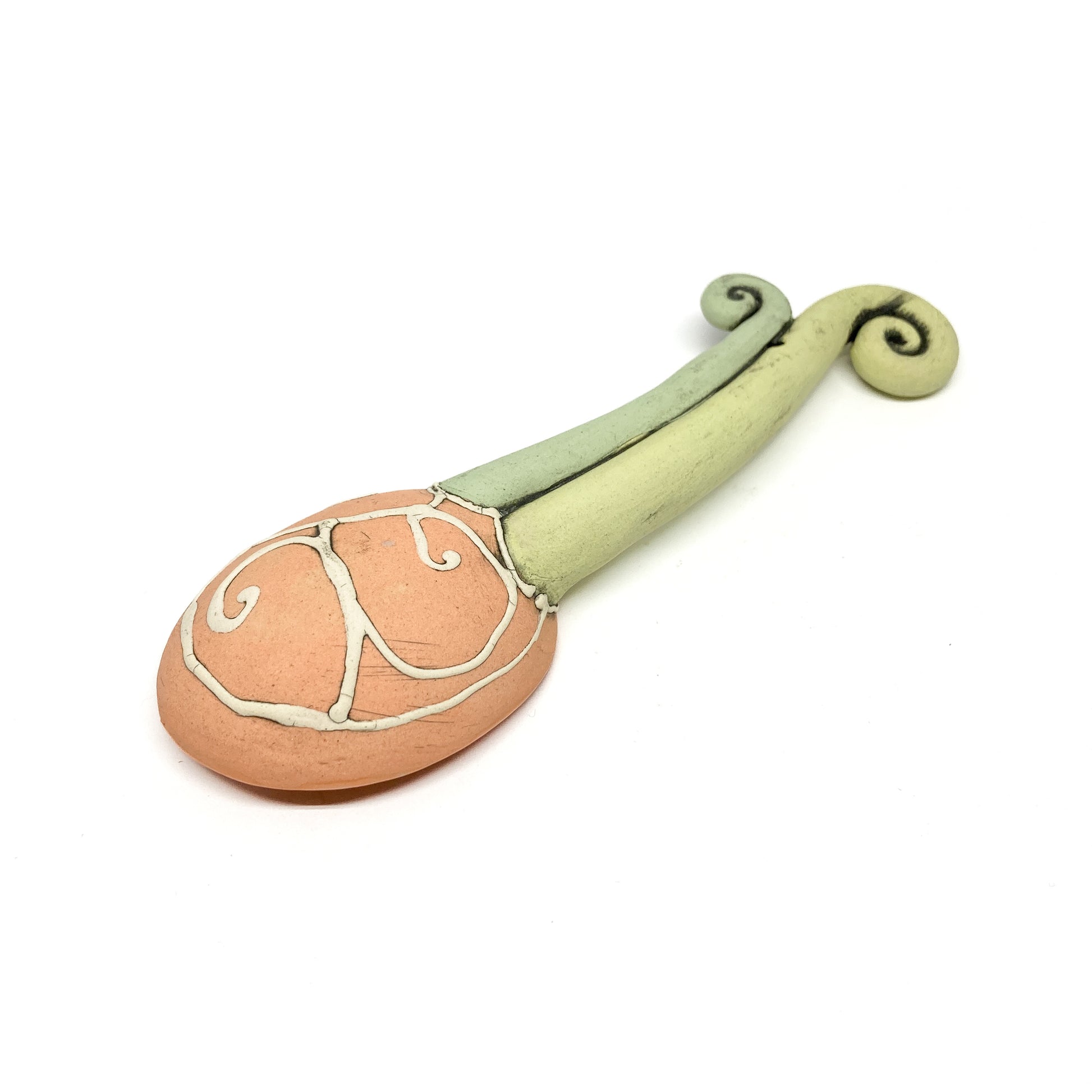 Back of a funky spoon with a textured blue bowl and white etched swirl designs, plus a sculpted handle.