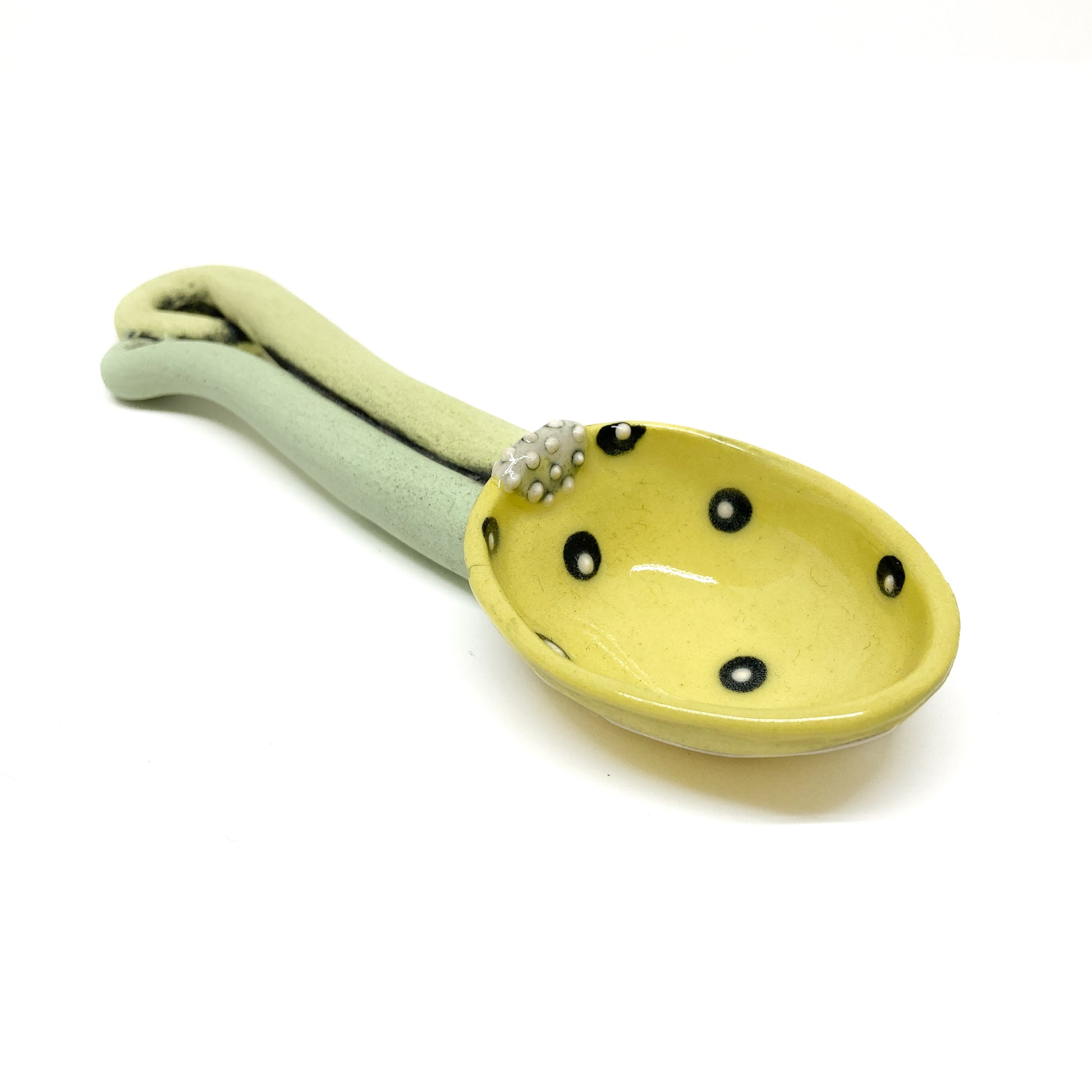Front view of funky spoon with polka-dot red bowl and twisted, dual-tone sculpted handle.
