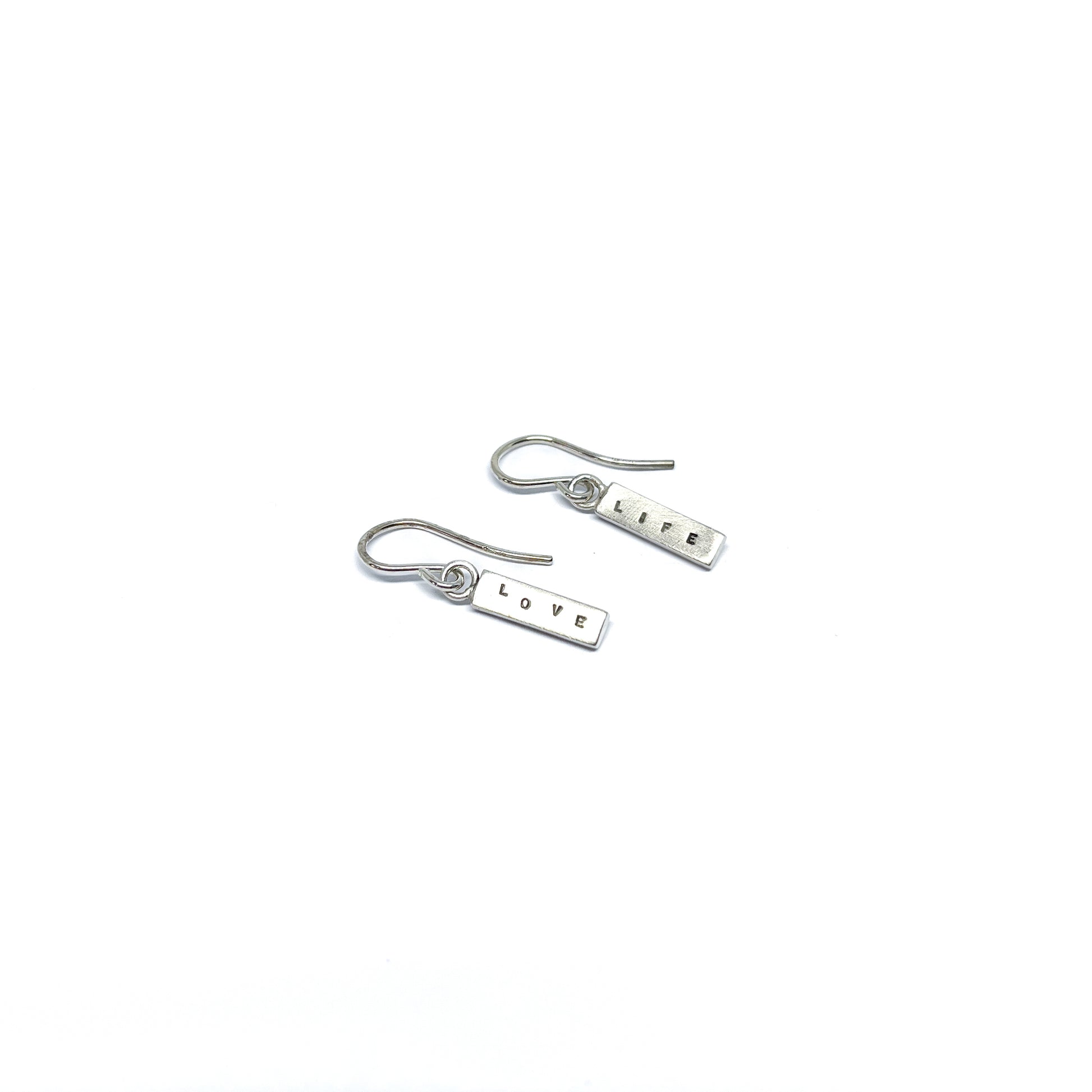 Two silver earrings with rectangular charms, one reads "LIFE" and the other "LOVE".