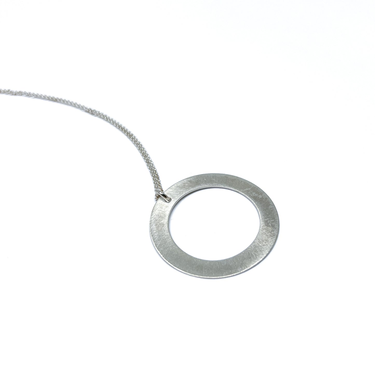 Silver necklace with a circular pendant, lying flat.