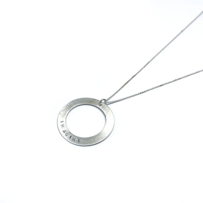 Silver necklace with a circular pendant engraved with the word "IMAGINE."