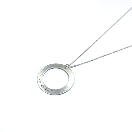 Silver necklace with a circular pendant engraved with the word "IMAGINE."